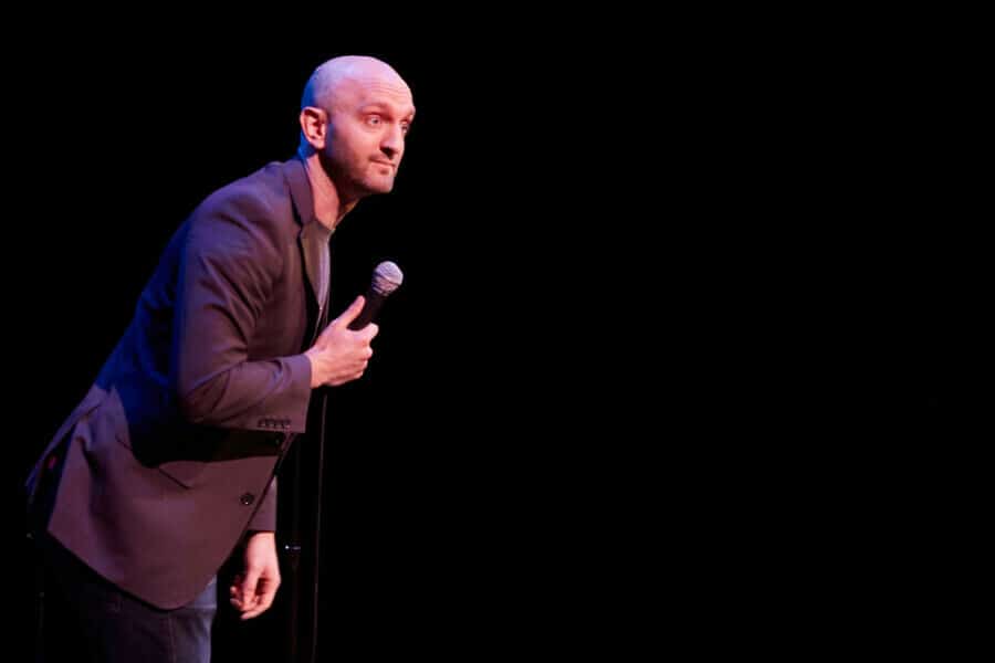 Paul Green in the void as he holds a mic in hand and leans closer to the audience