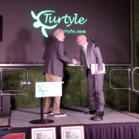 Paul shaking the hands of someone on stage at the Turtyle